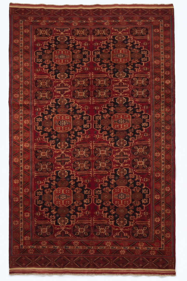 Decorative red and black patterned rug on a white background